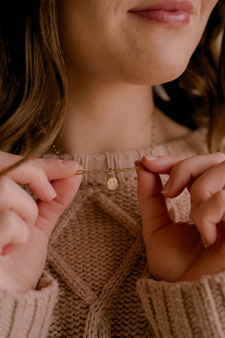 Close-up of a person wearing a gold necklace with a small pendant.