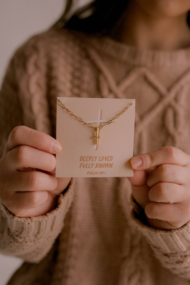 Person holding a gold necklace on a card with text