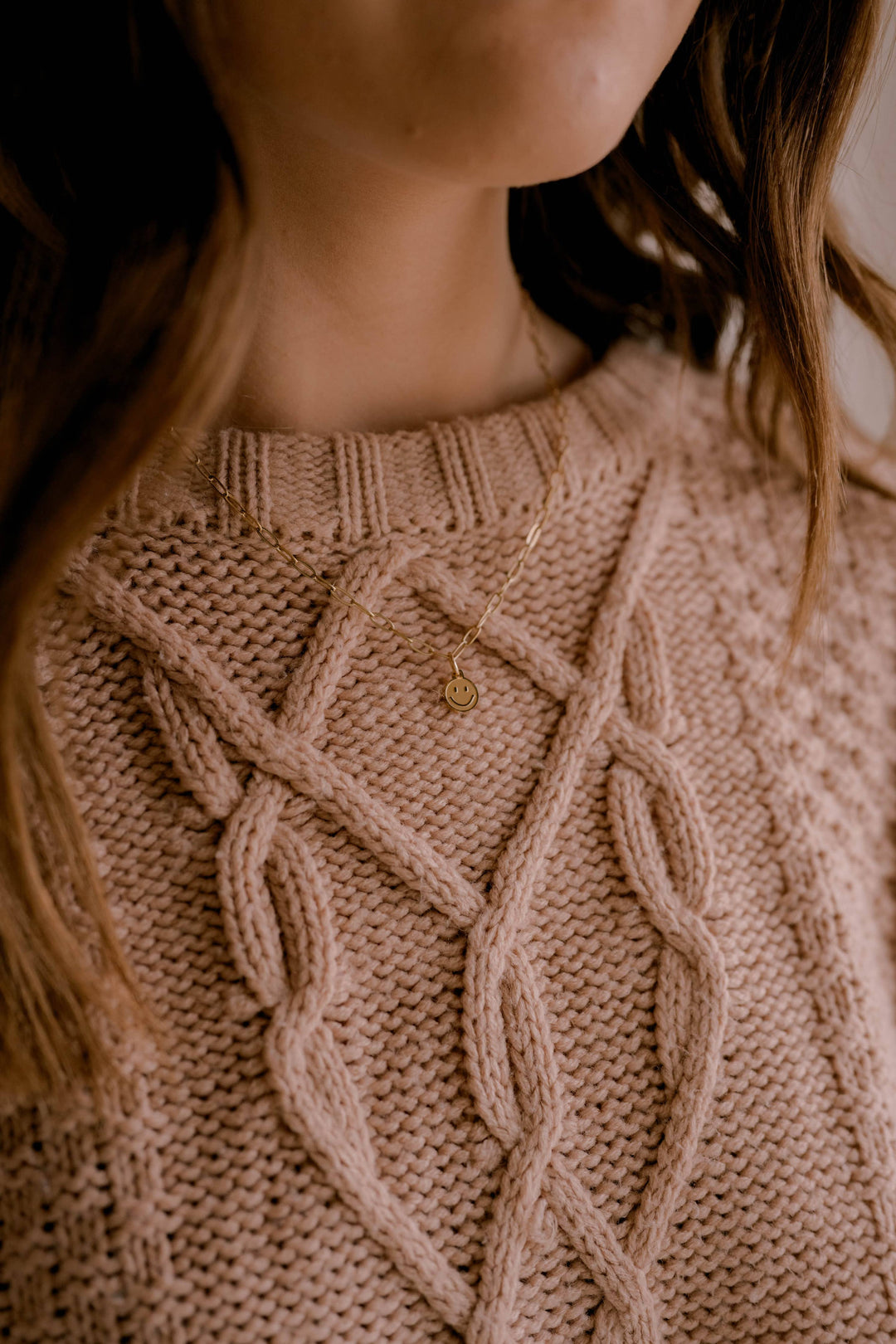 Close-up of a person wearing a beige knitted sweater with a subtle pattern.