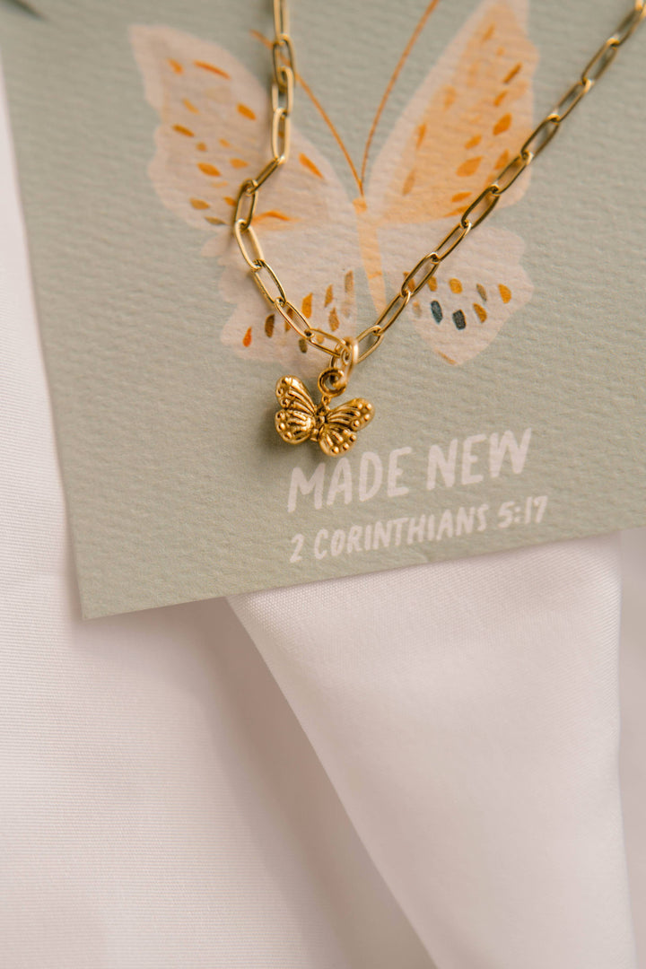 Gold butterfly necklace on a card with butterfly design and 'Made New' text.
