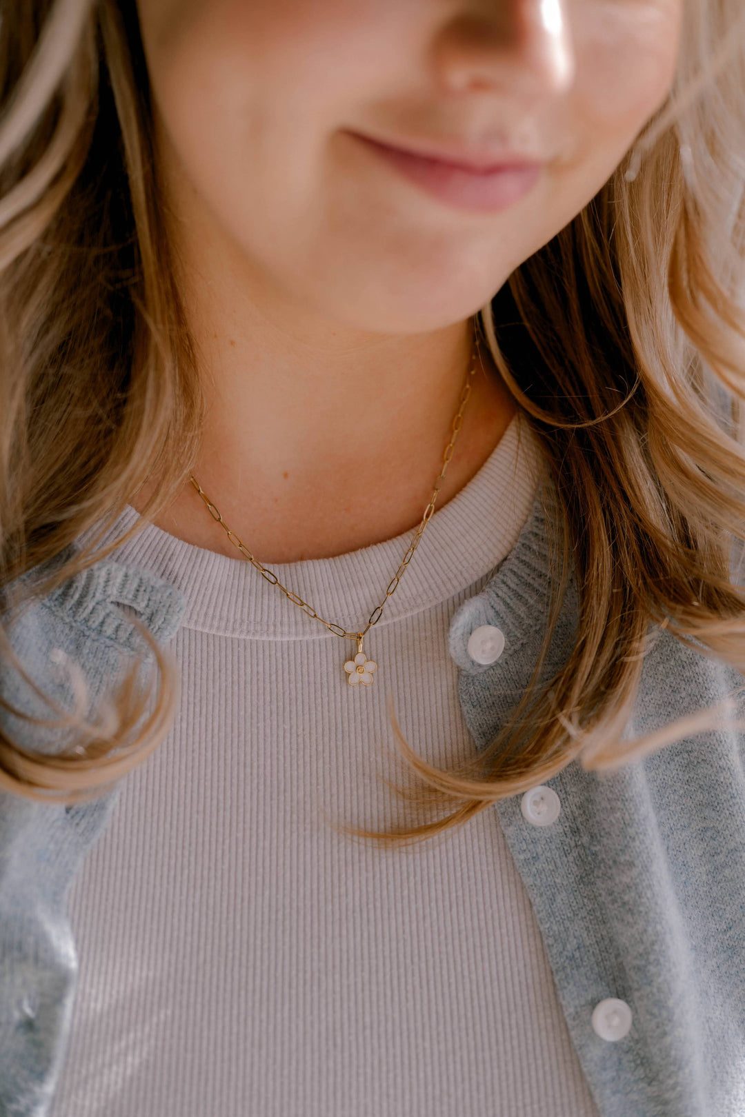 Close-up of a person wearing a delicate necklace with a light background