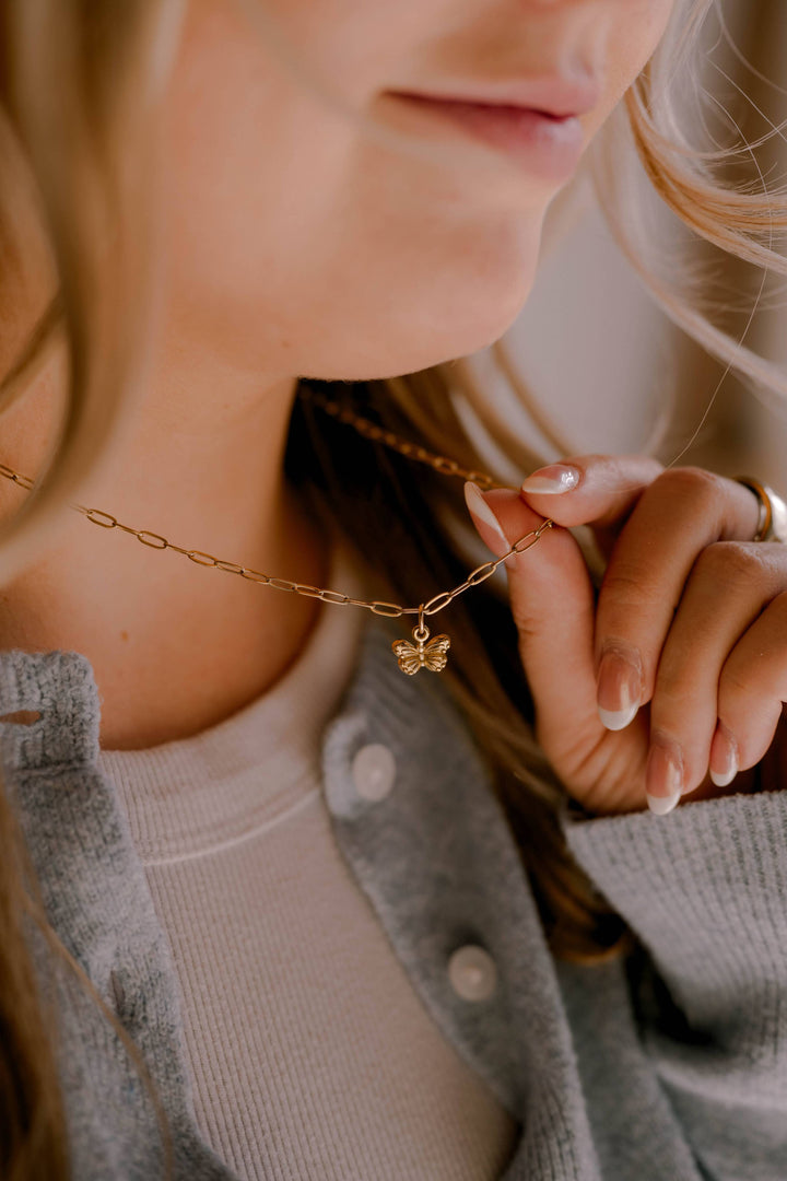 Close-up of a person wearing a gold necklace with a small pendant.