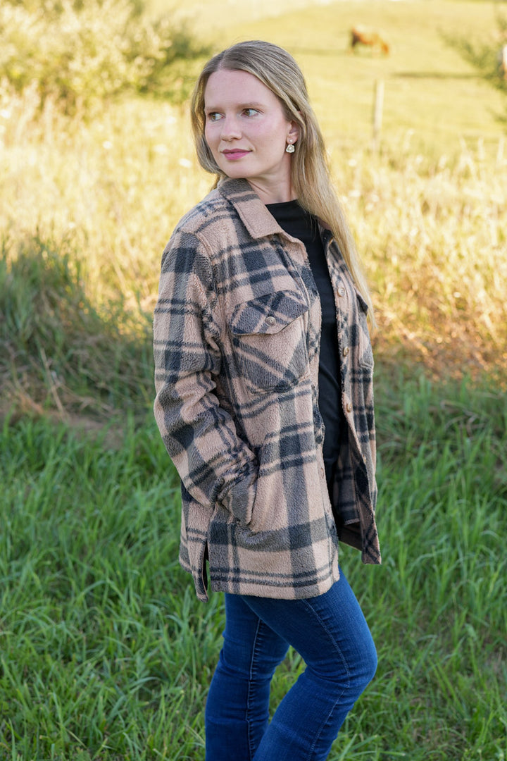 Woman wearing a black and tan plaid fleece jacket in a natural setting