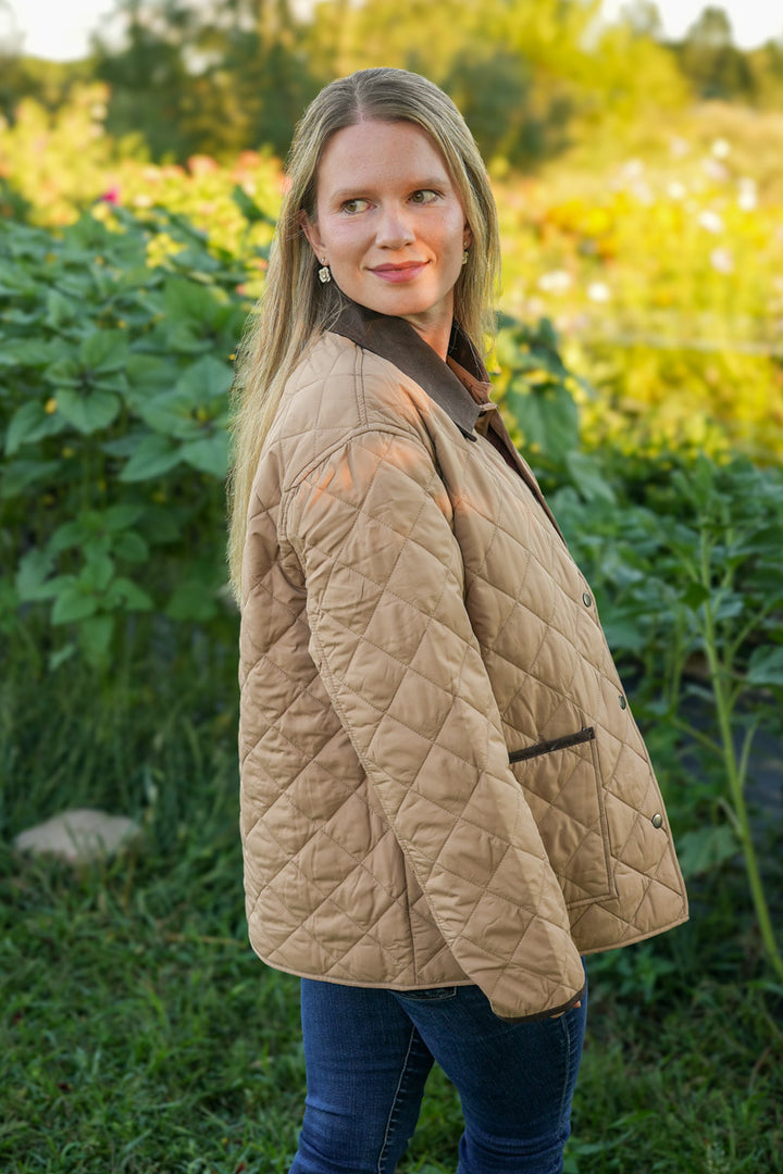 Woman wearing a quilted beige jacket standing in a garden