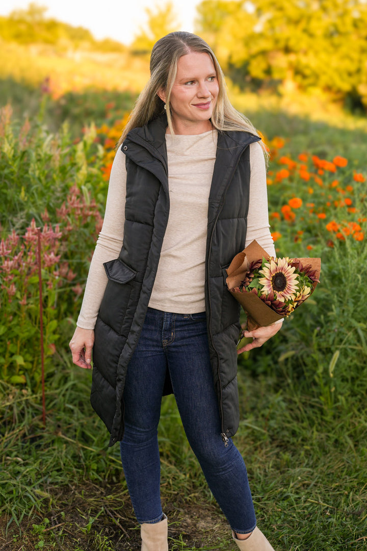 Woman holding a bouquet of flowers in a field with wildflowers and trees in the background