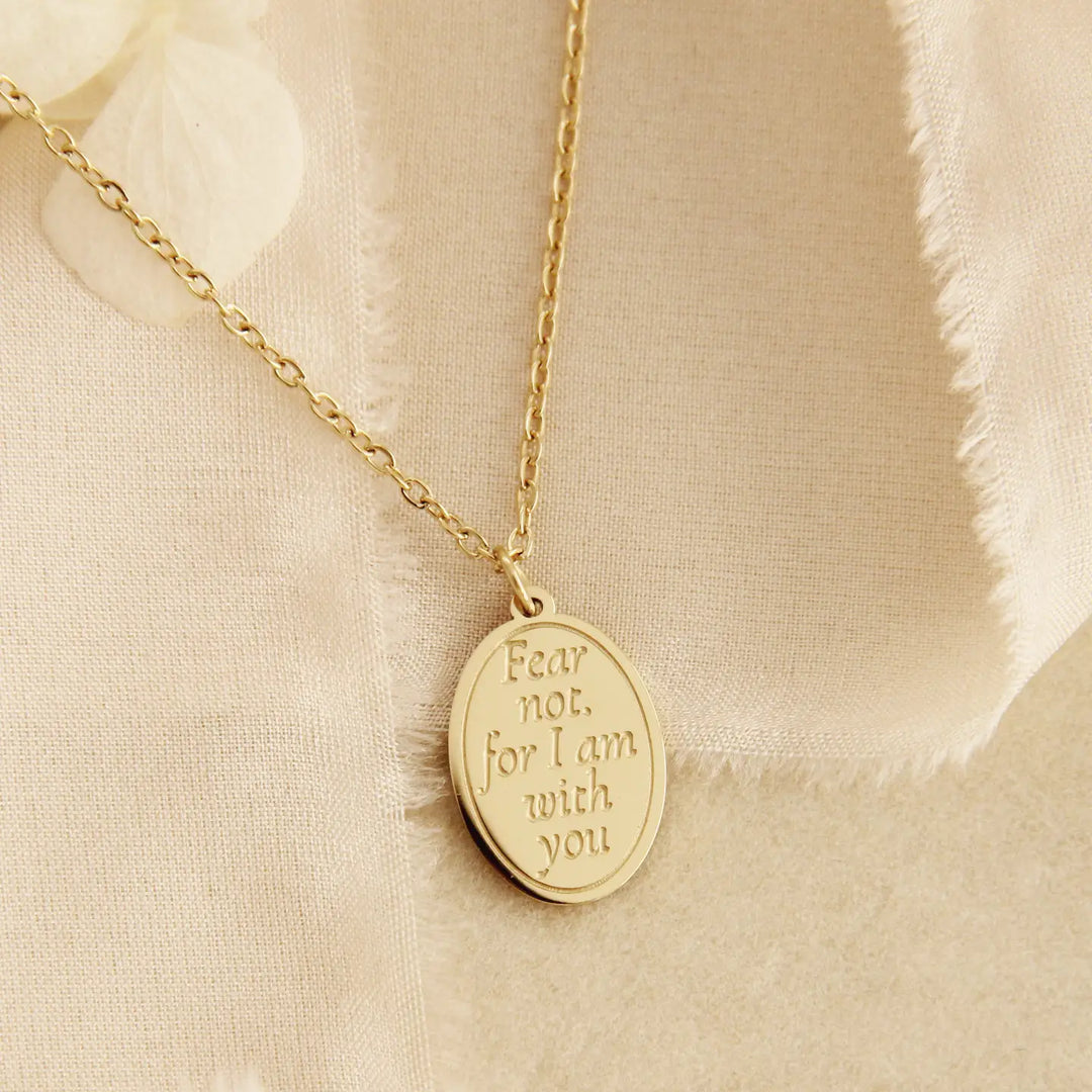 Gold Fear Not, for I am with you engraved pendant necklace on a beige fabric background