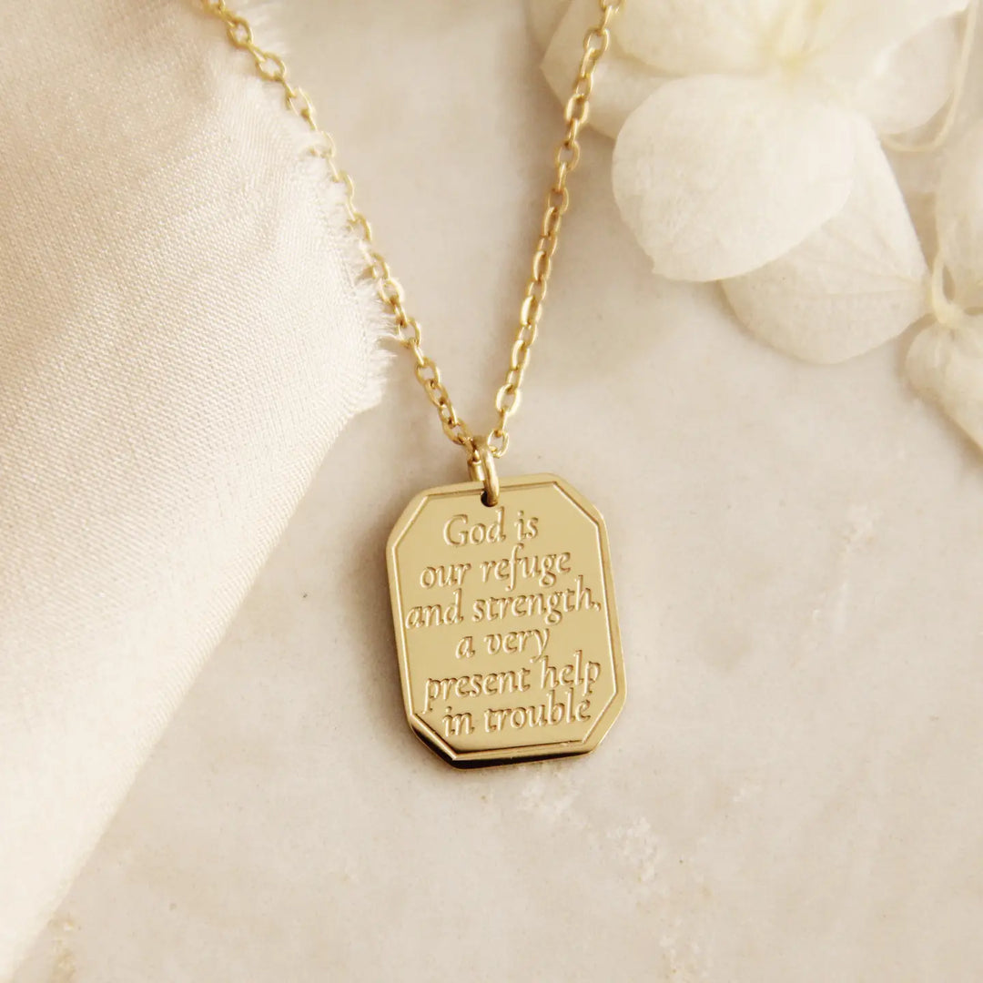 Gold Christian necklace with an engraved pendant that says "God is our refuge and strength, a very present help in trouble"