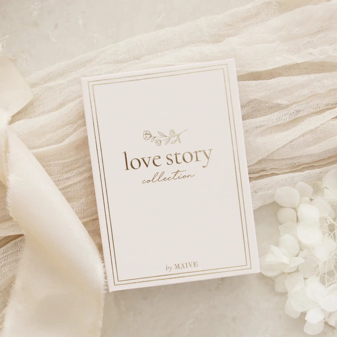 Jewelry box with 'Love Story Collection' text on a soft fabric background
