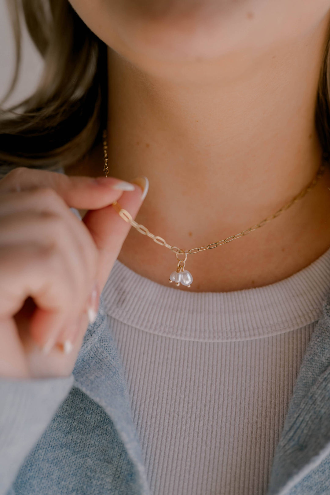 Close-up of a delicate gold necklace with a small pendant worn by a person.