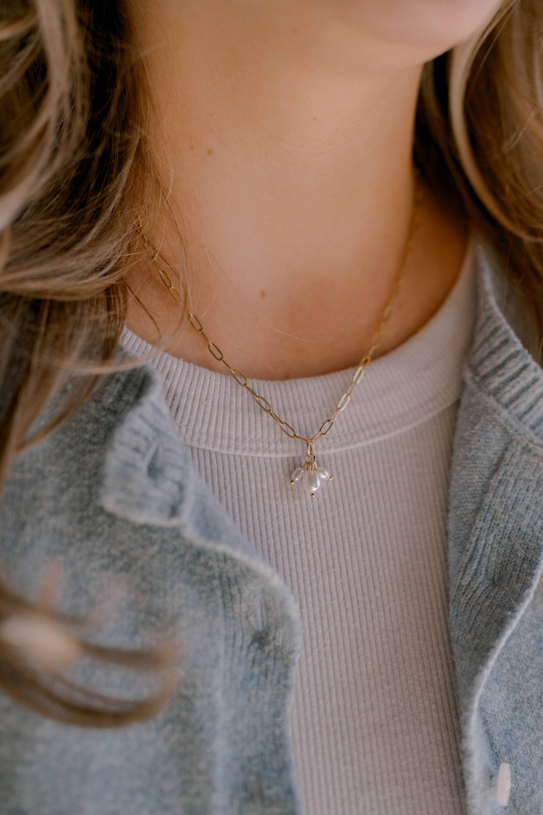 Close-up of a person wearing a gold necklace with a pendant.
