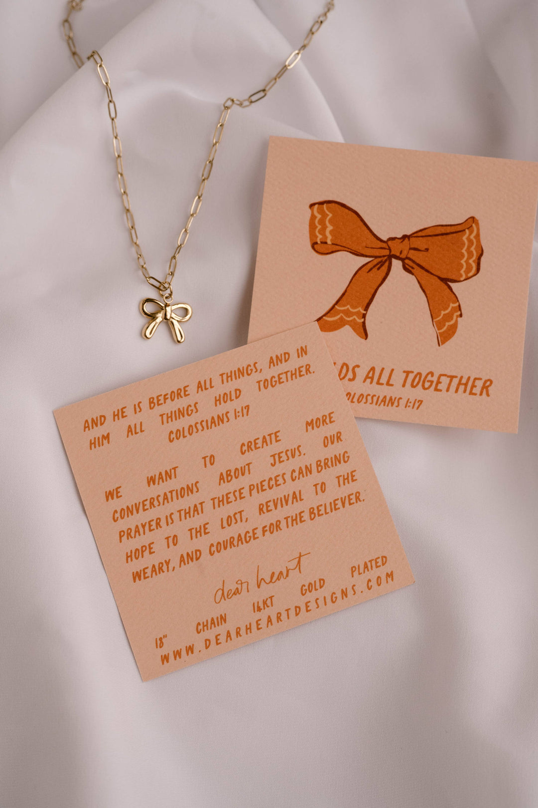 Necklace with a bow charm on a card with text and a printed bow design.