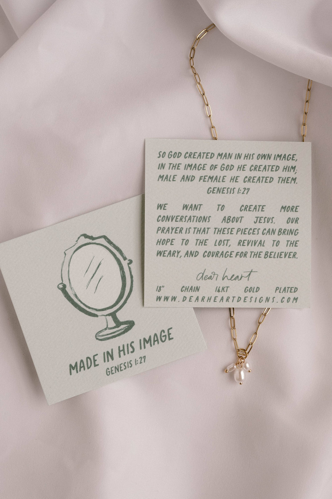 Gold necklace with a pendant on a card featuring text and branding.