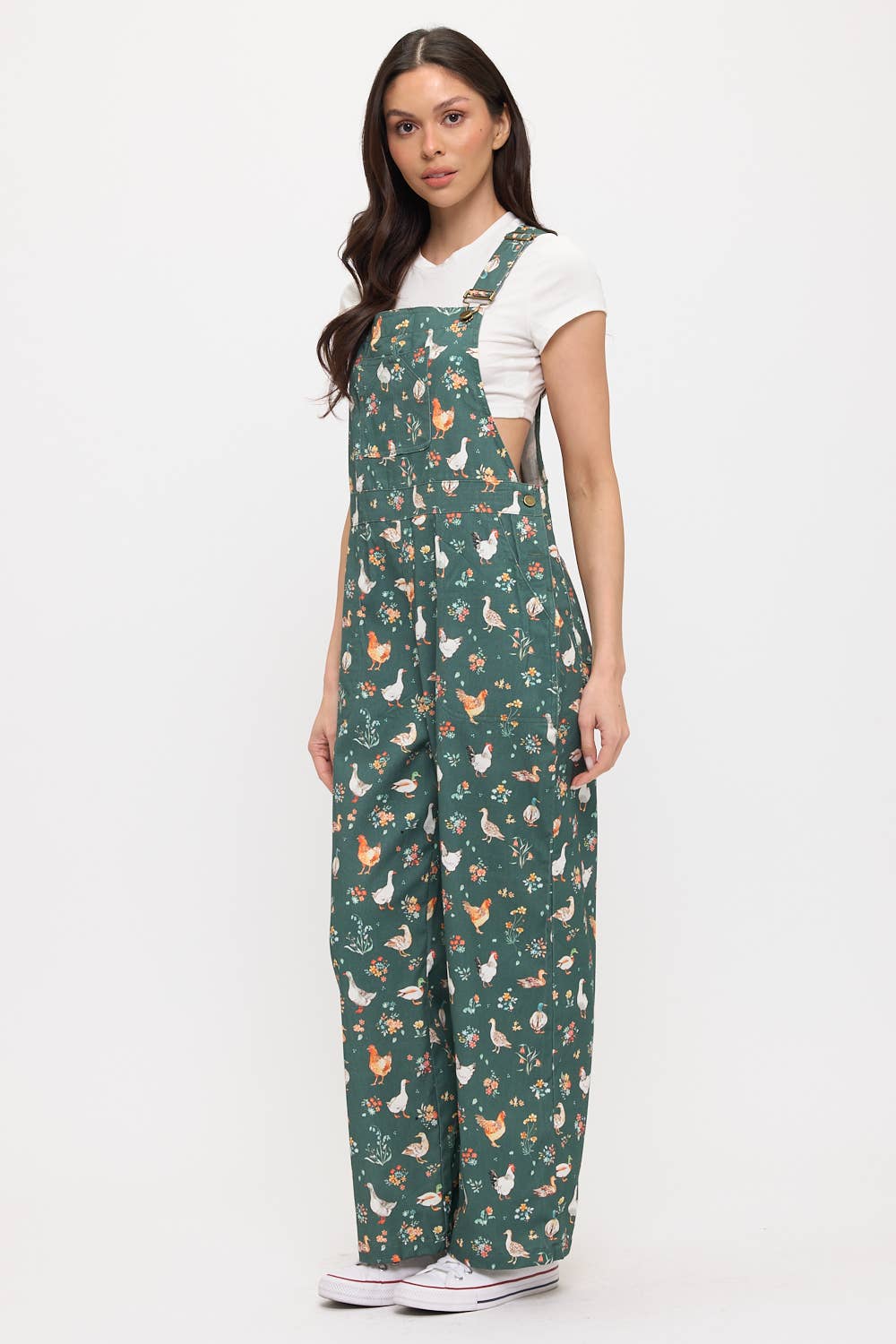 Woman wearing dark green overalls with ducks and chickens on a white background