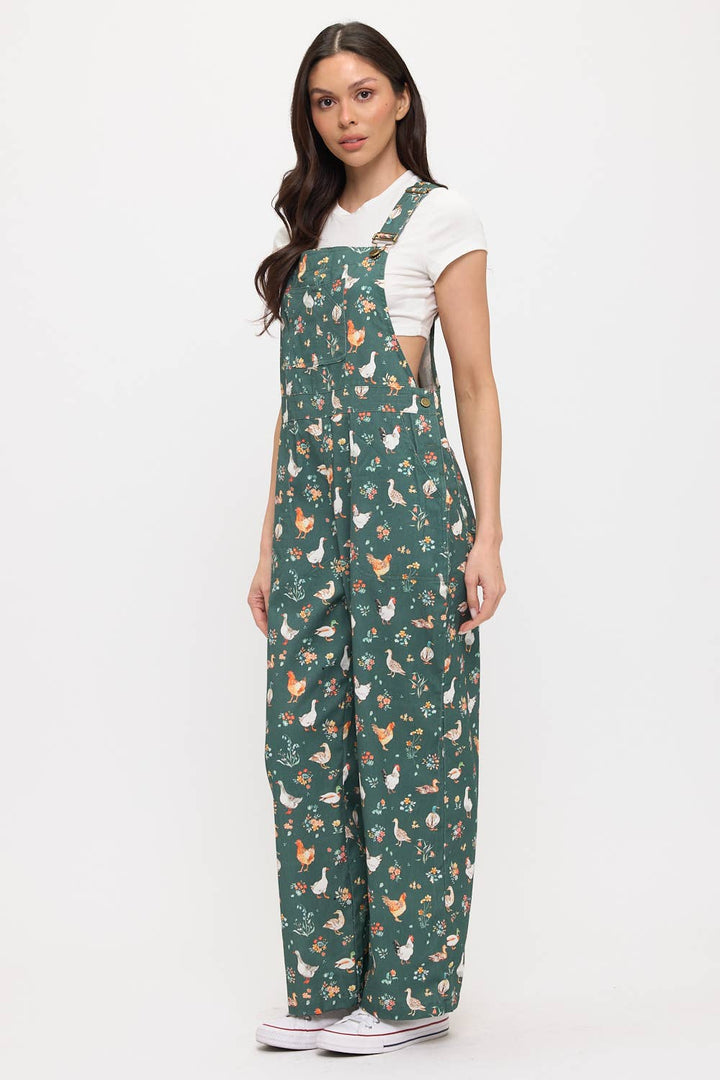 Woman wearing dark green overalls with ducks and chickens on a white background