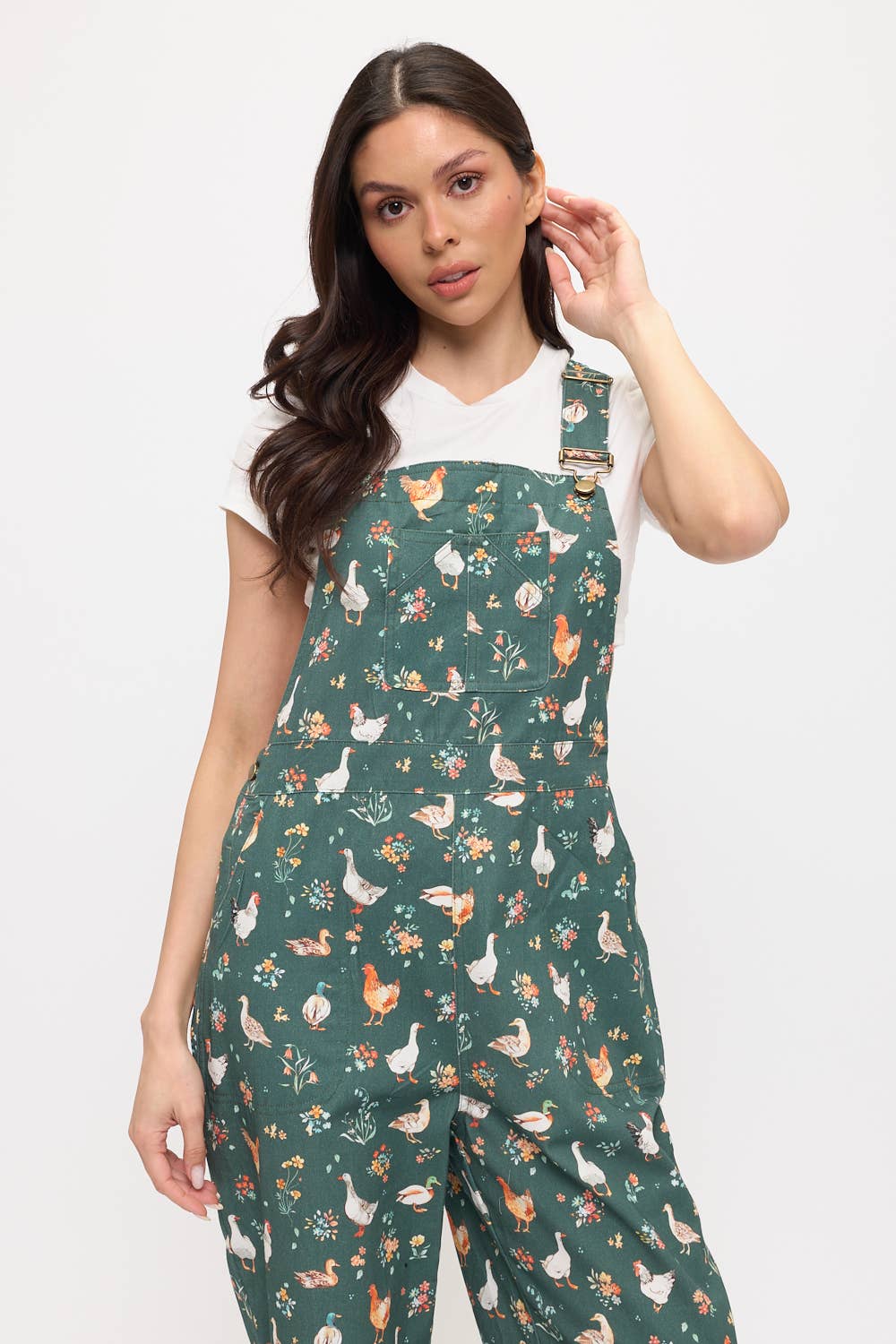 Woman wearing green ducks and chickens patterned overalls on a white background