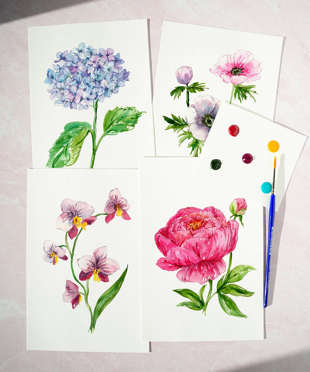 Set of floral watercolor paintings on paper with a paintbrush.