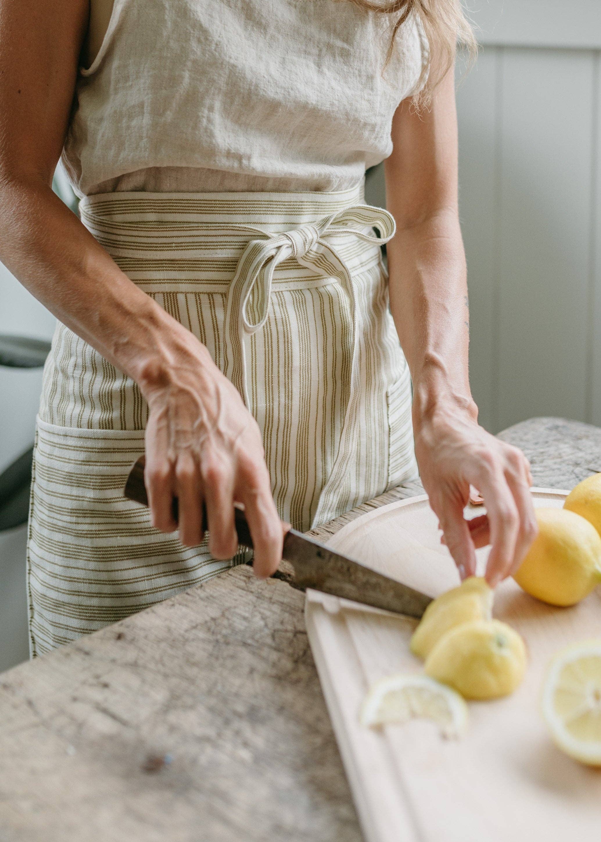 Person cutting lemons on a wooden board with a knife