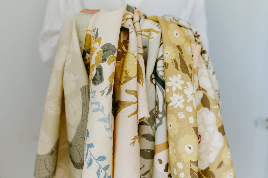 Collection of floral-patterned cloths draped over a person against a plain background