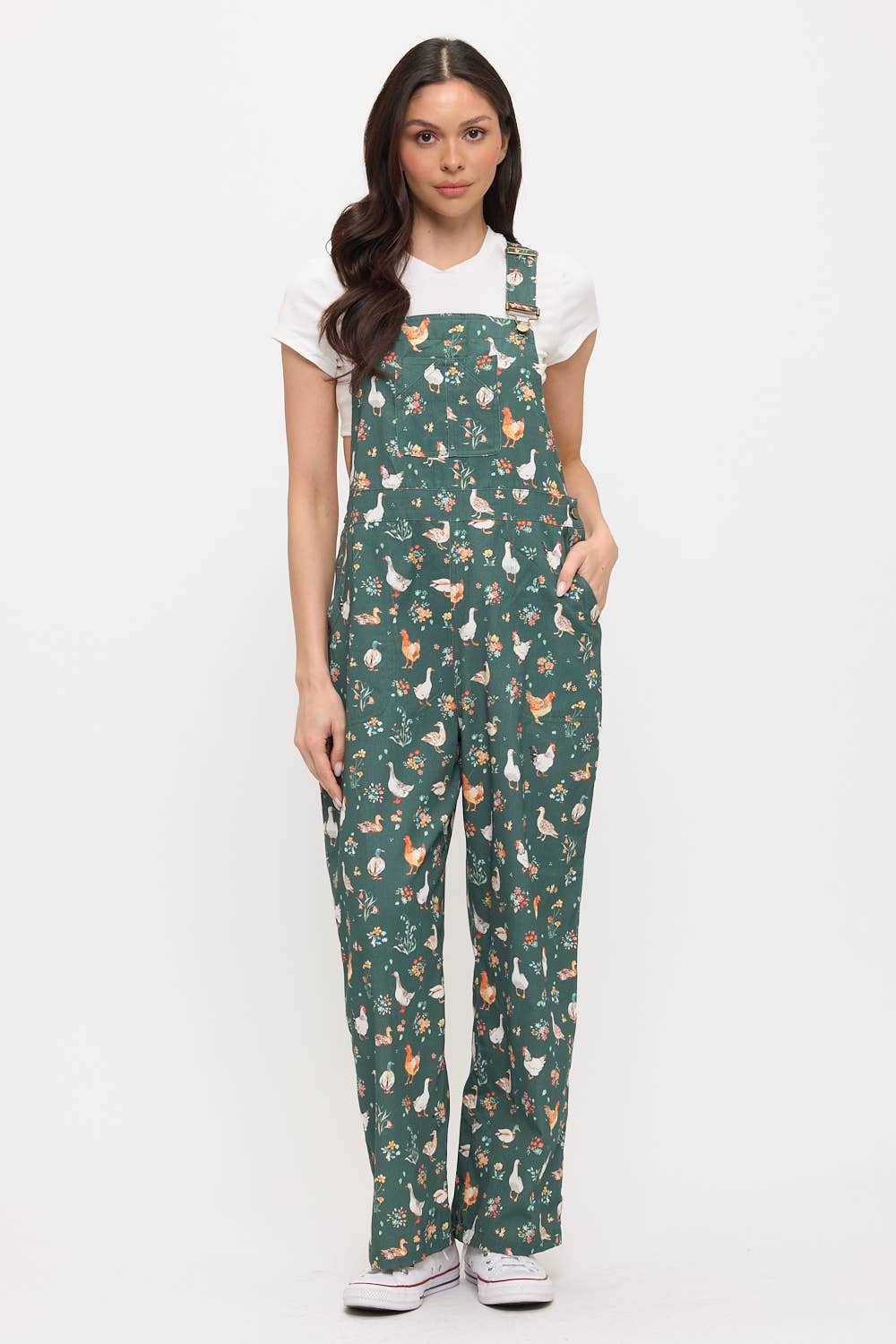 Woman wearing a green patterned overalls with ducks and chickens on a white background