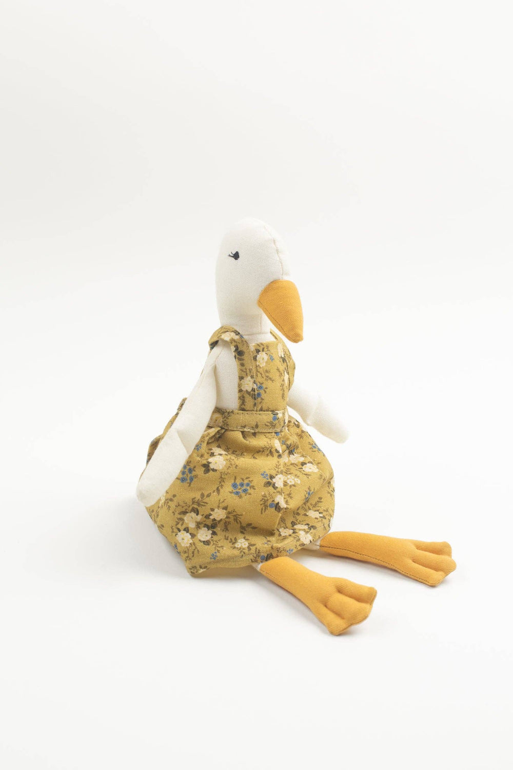 Stuffed toy duck wearing a floral dress on a white background