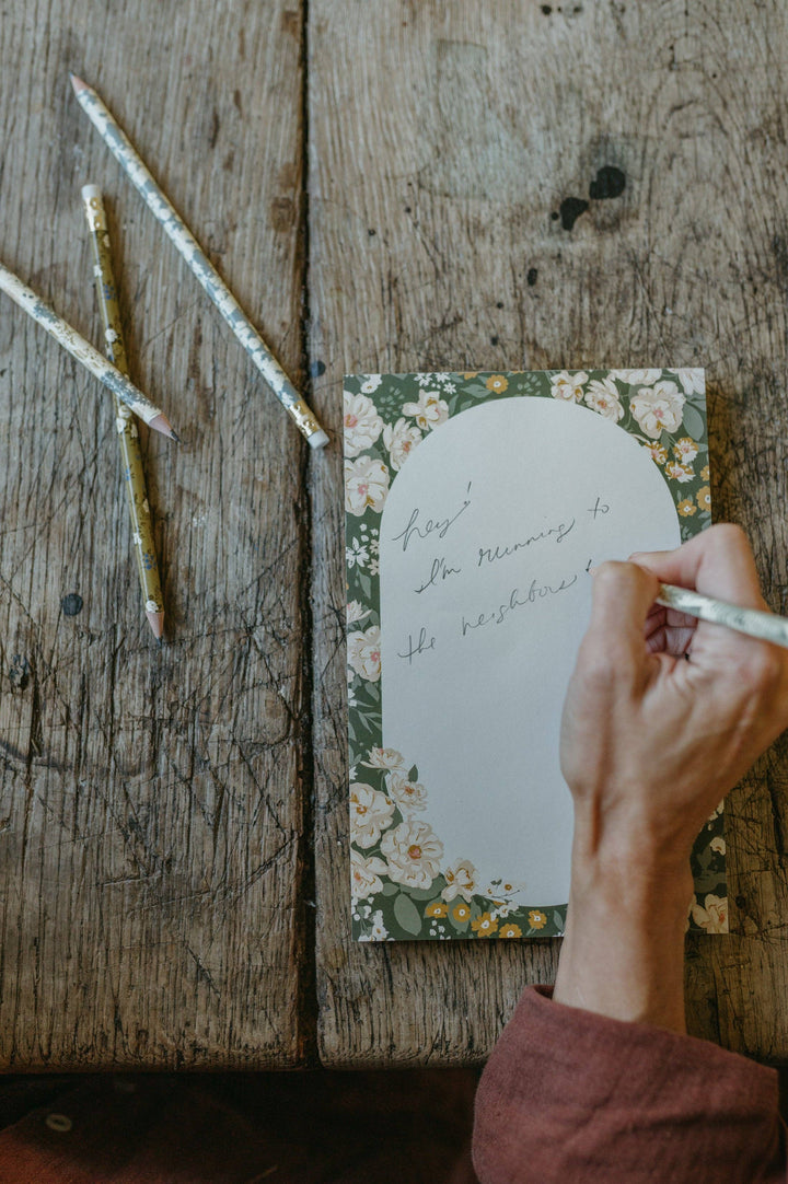 Handwritten card with floral design on a rustic wooden surface