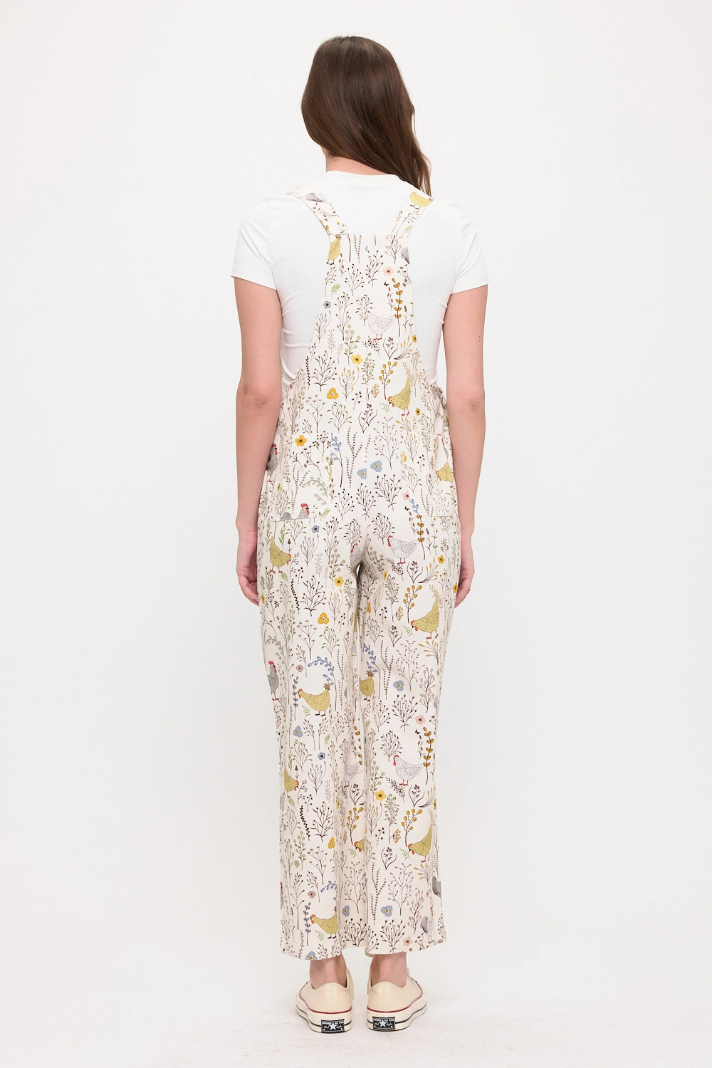 Woman wearing gardening overalls with chickens, roosters and botanicals