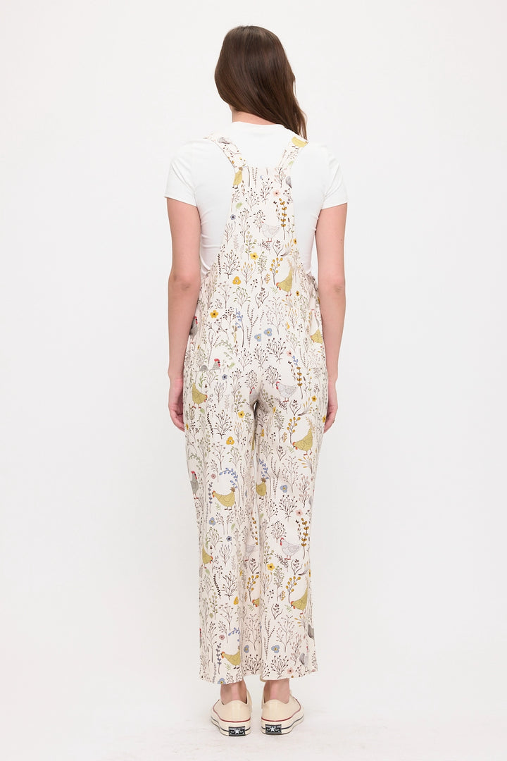 Woman wearing gardening overalls with chickens, roosters and botanicals