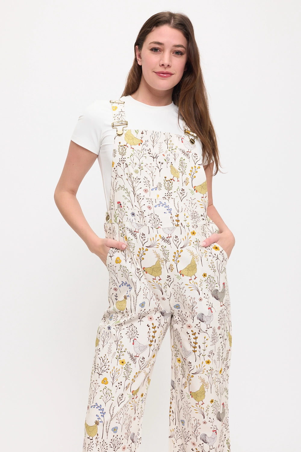 Woman wearing printed overalls featuring chickens, roosters, and flowers