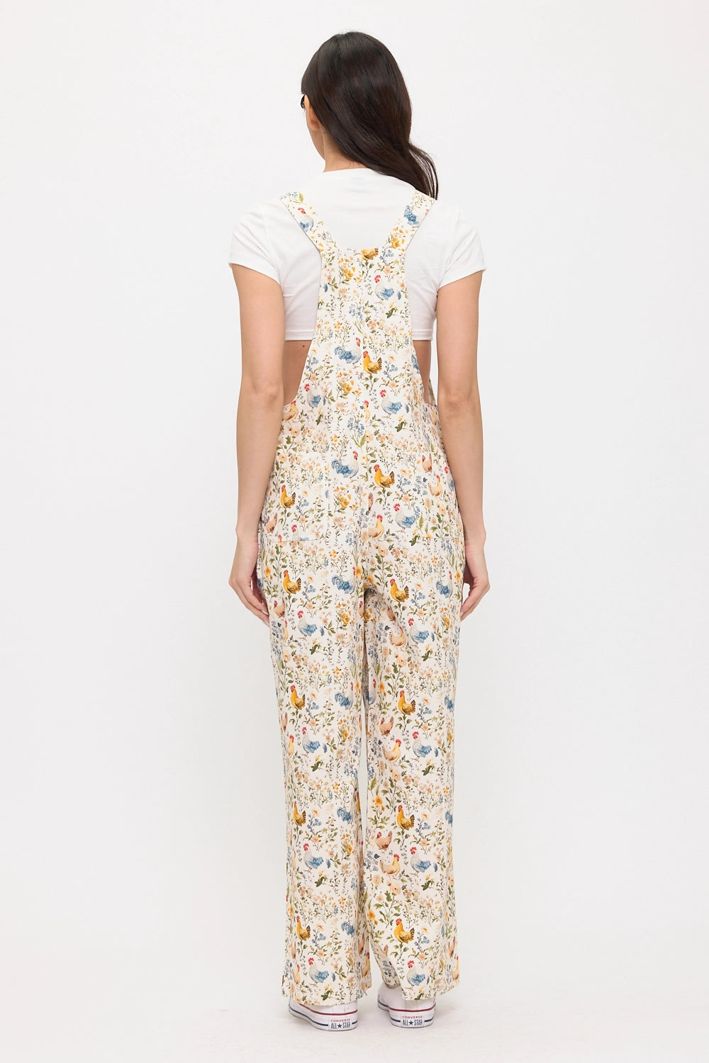 Person wearing a chicken and floral patterned jumpsuit on a white background