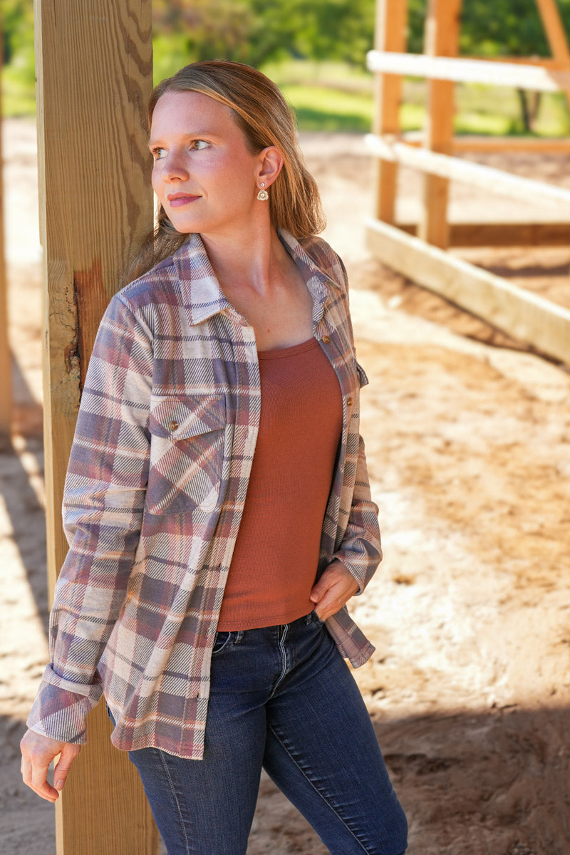 Woman wearing a plaid shirt and brown top outdoors