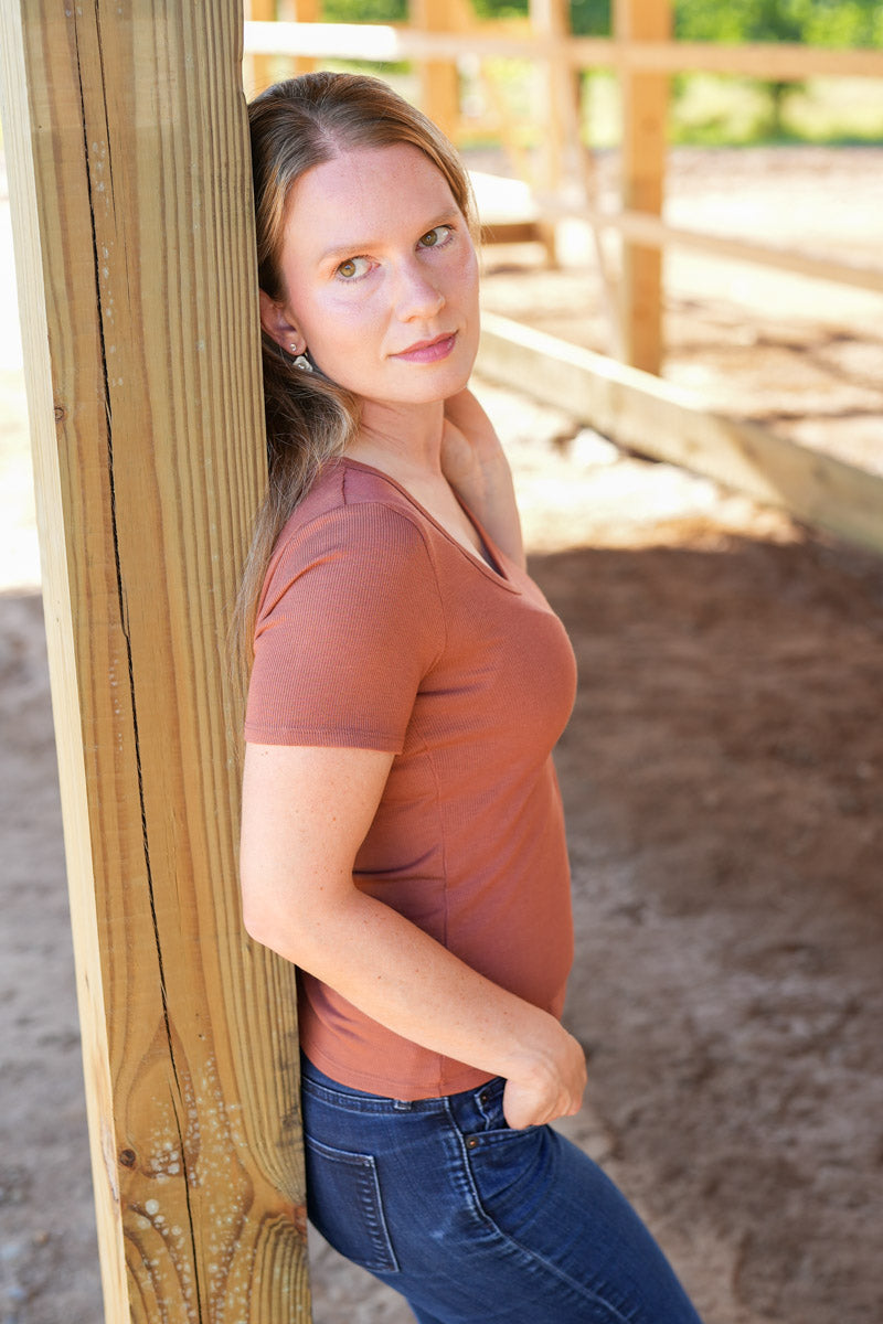 Woman leaning against a wooden post outdoors