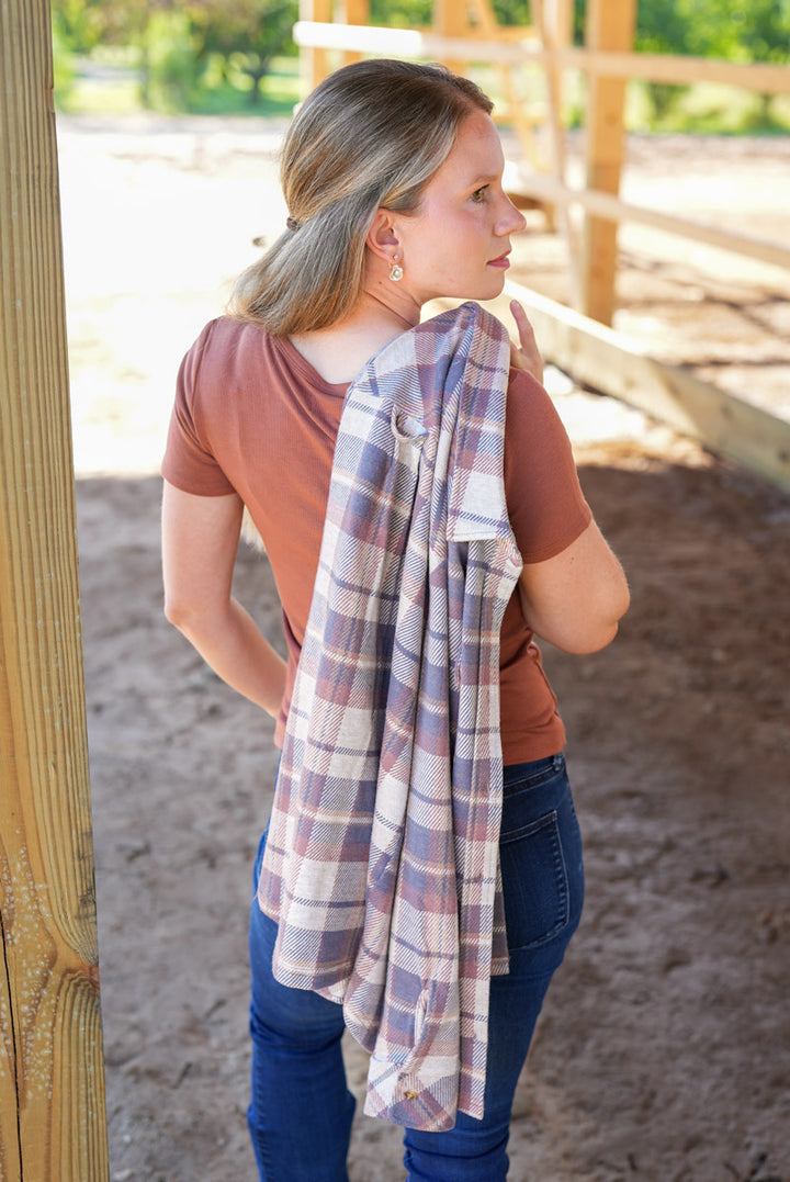 Woman wearing a plaid shirt over a brown top in an outdoor setting