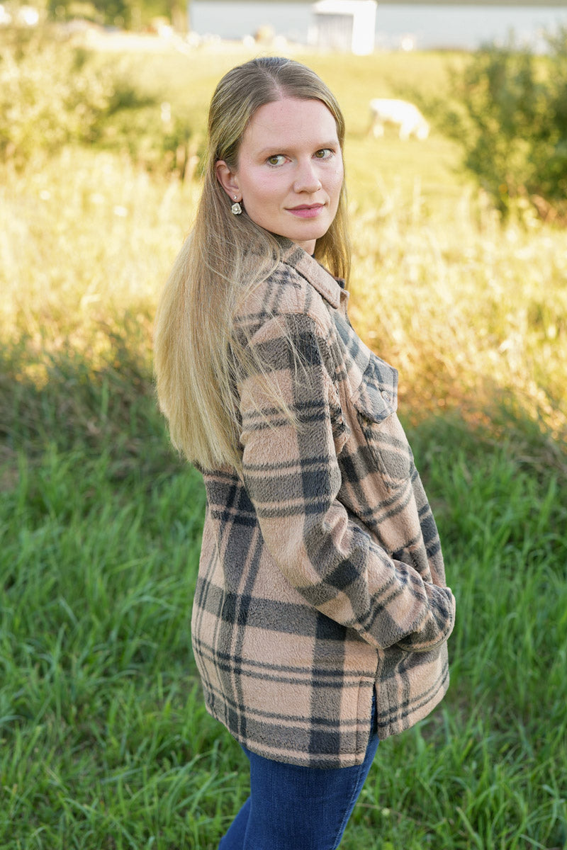 Woman wearing a black and tan plaid fleece jacket in a natural setting