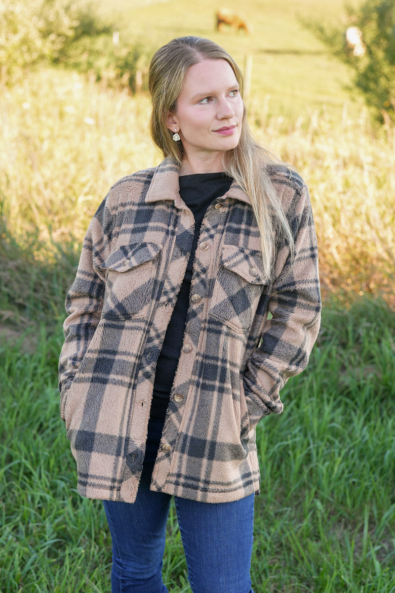 Woman wearing a black and tan plaid fleece jacket in a natural setting