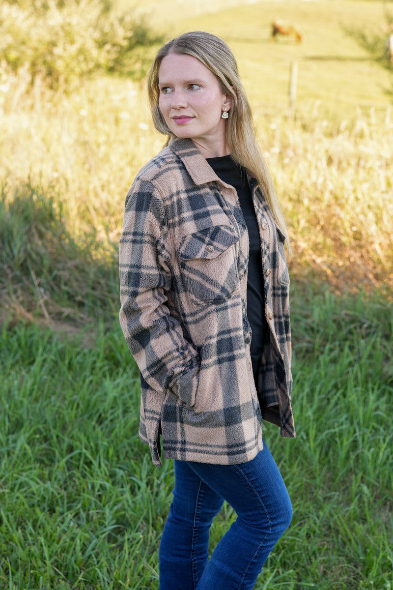 Woman wearing a black and tan plaid fleece jacket in a natural setting
