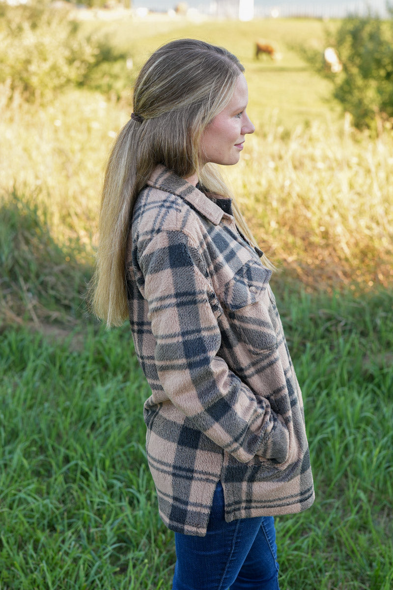 Woman wearing a black and tan plaid fleece jacket in a natural setting