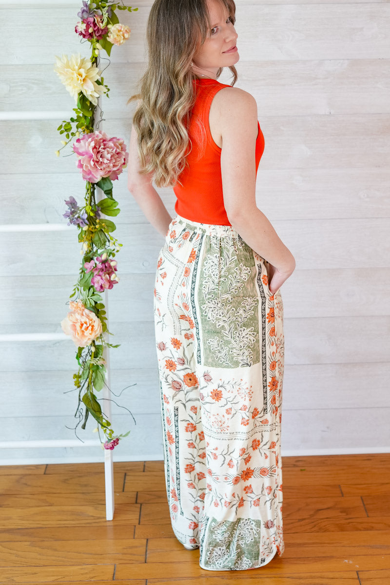 Woman wearing a red tank top and vintage floral skirt with a decorative flower arrangement on a white background