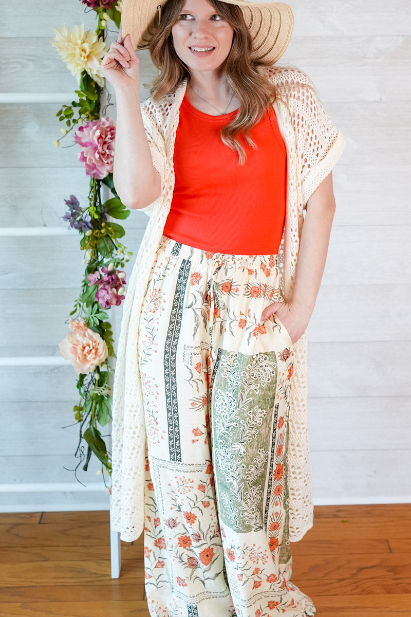 Woman wearing a red top and floral kimono-style garment with a white background