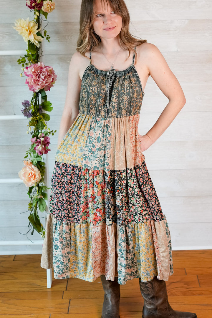 Woman wearing a patchwork dress with floral patterns in a home setting.