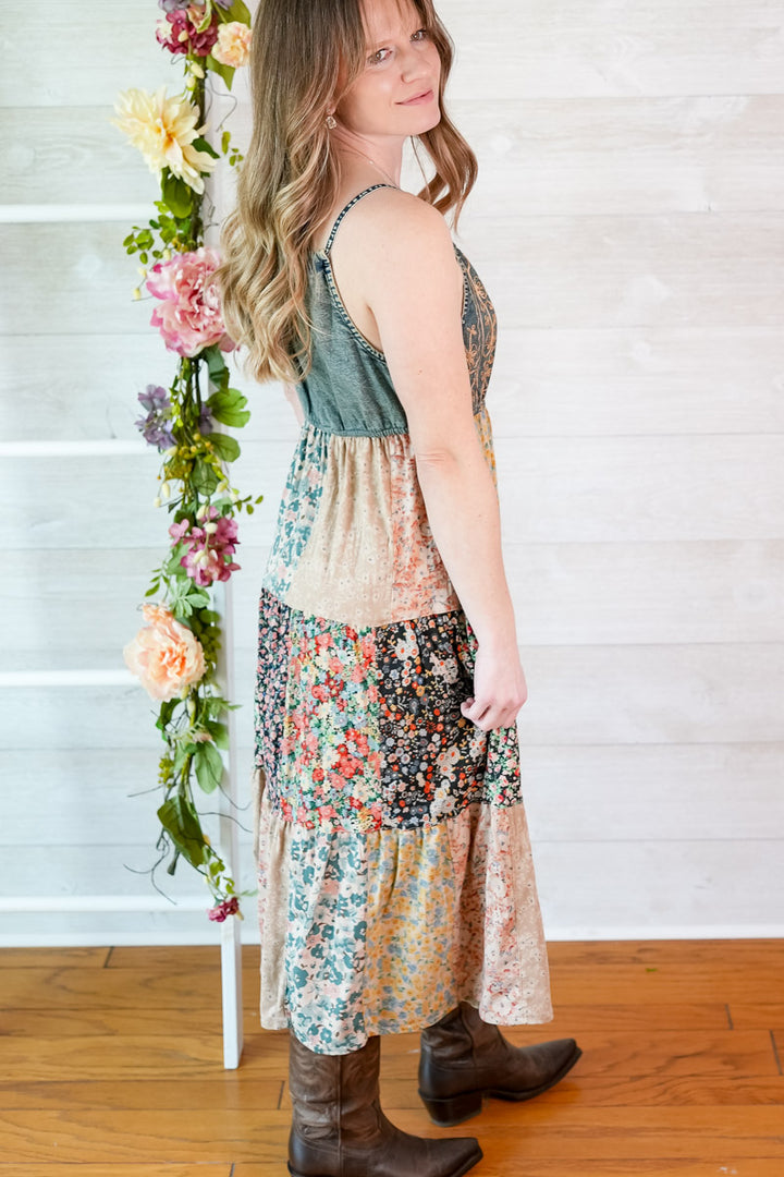 Woman wearing a floral dress standing next to a floral arrangement indoors.