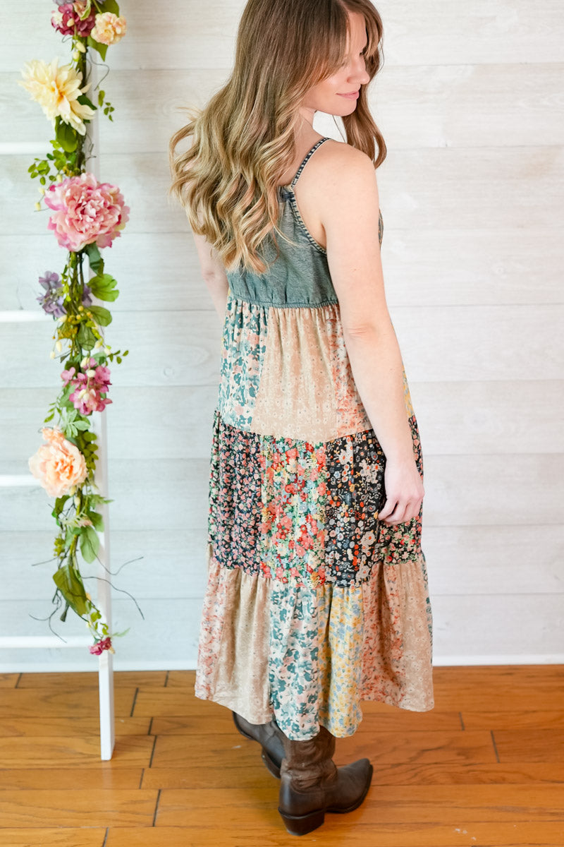 Woman wearing a layered dress with floral patterns against a white wall with floral decorations.