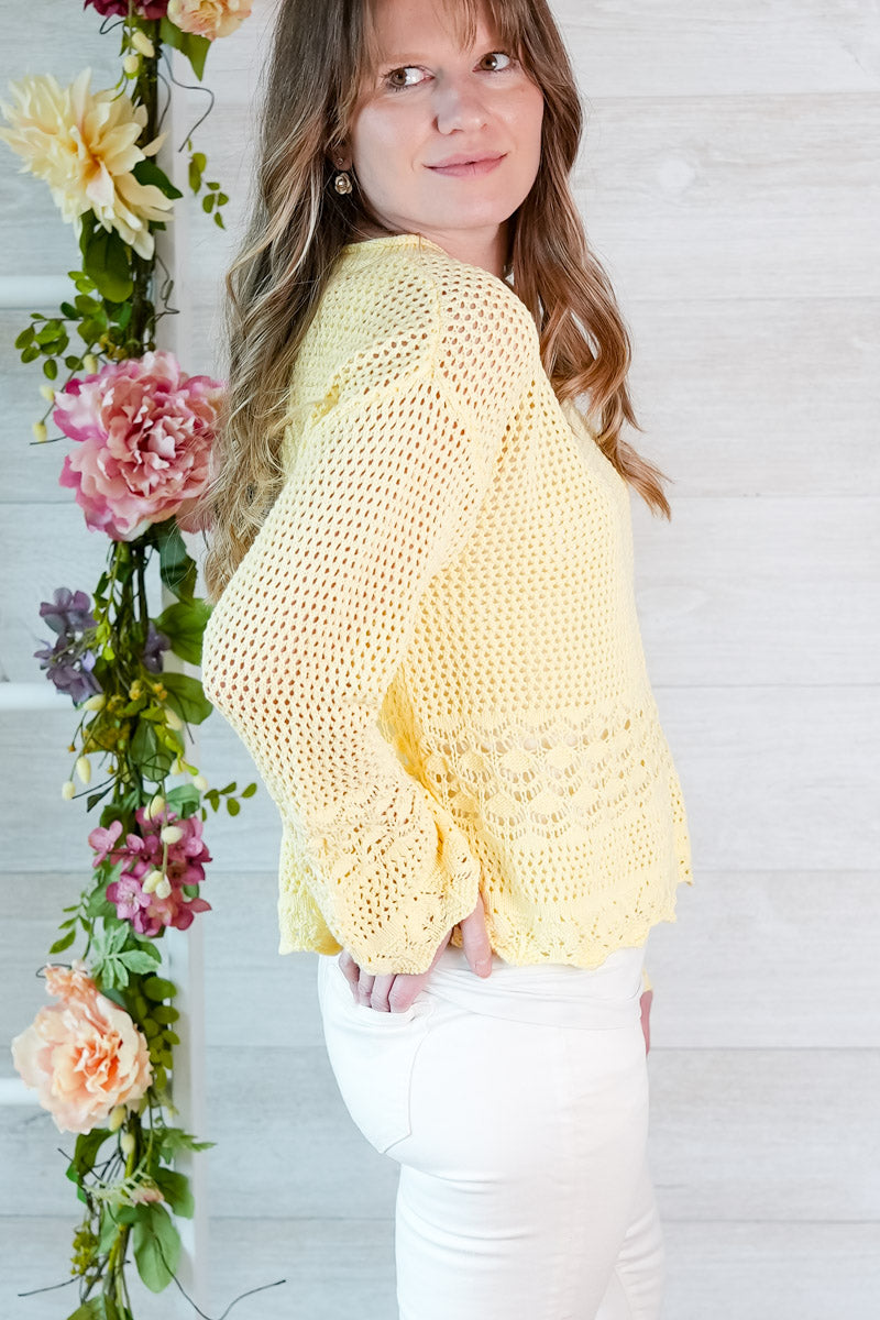 Woman wearing a yellow crochet top with floral decorations in the background