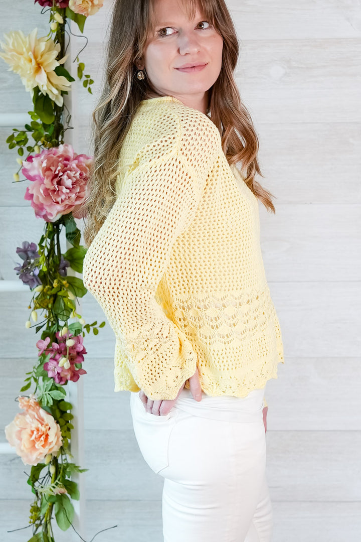 Woman wearing a yellow crochet top with floral decorations in the background
