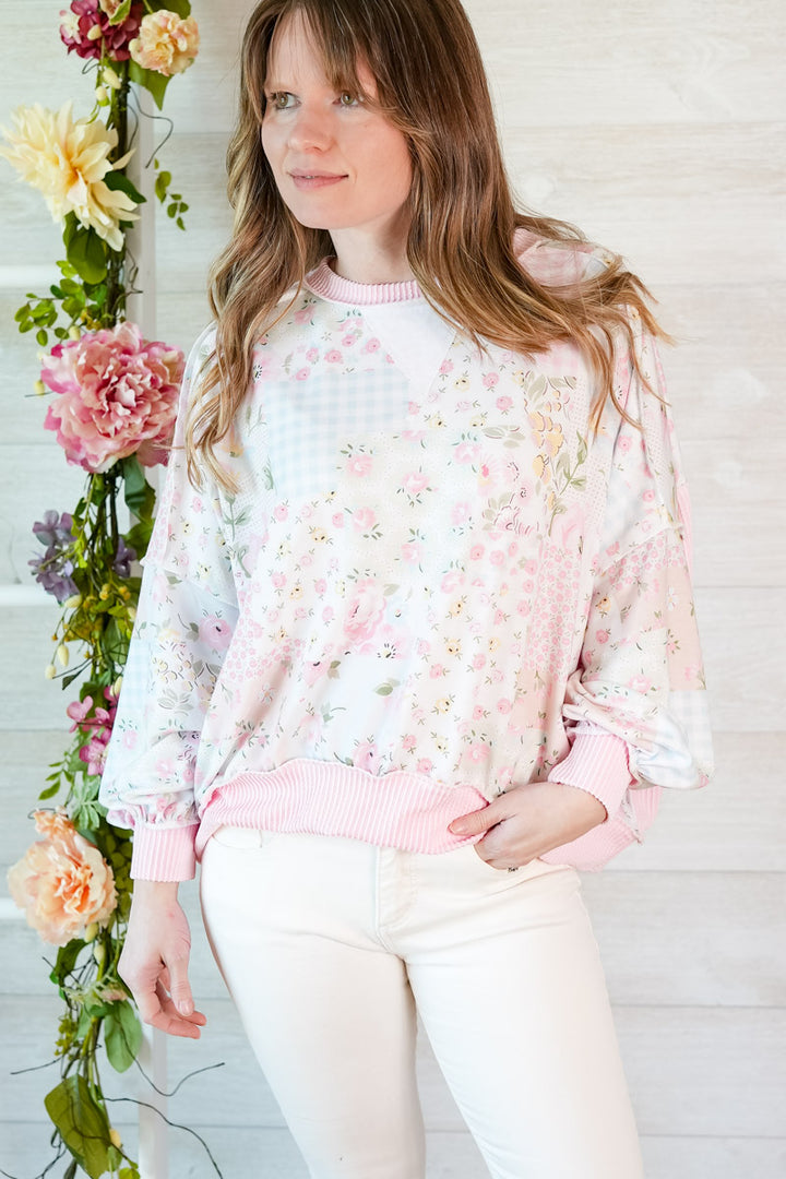 Woman wearing a floral patchwork blouse with a white background and floral decorations.