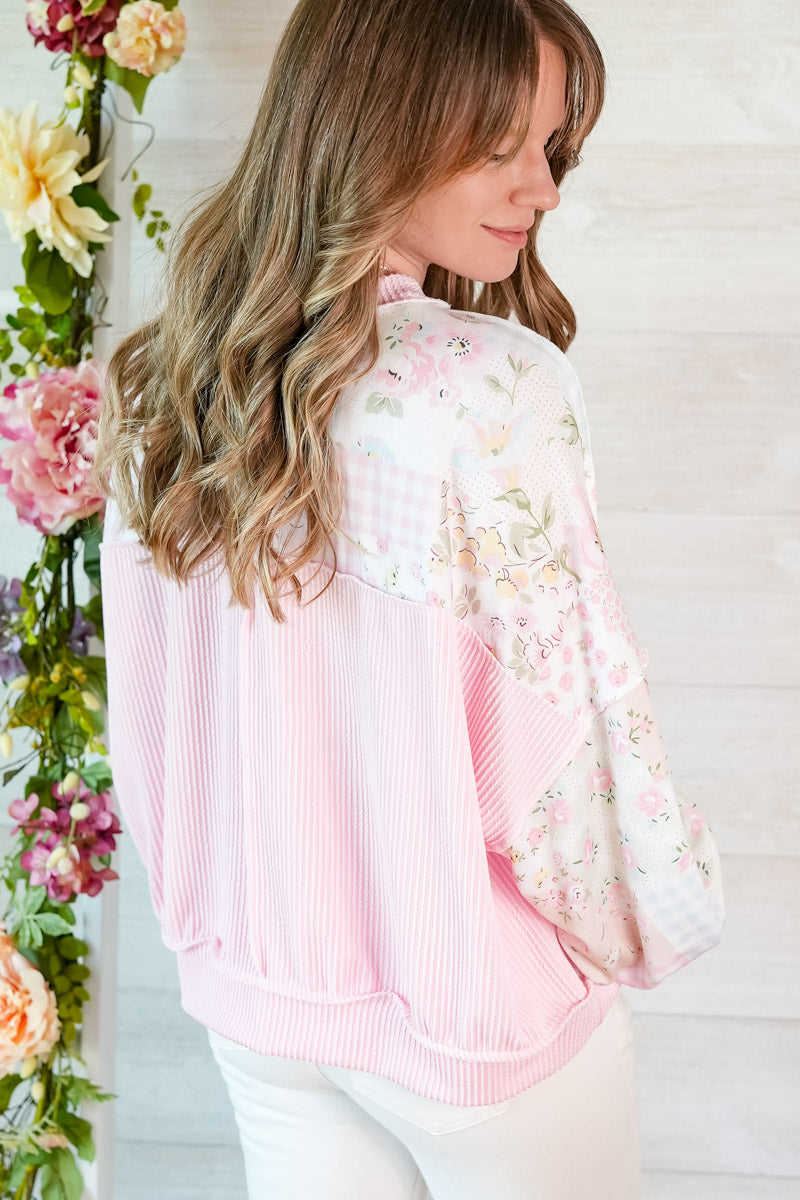 Woman wearing a pink floral patchwork blouse with a white background and floral decorations.