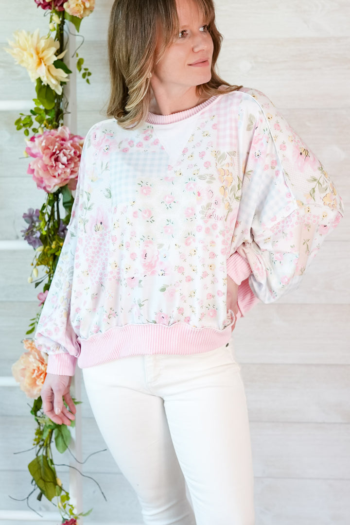 Woman wearing a multi-color floral patchwork top with a white background and floral decorations.