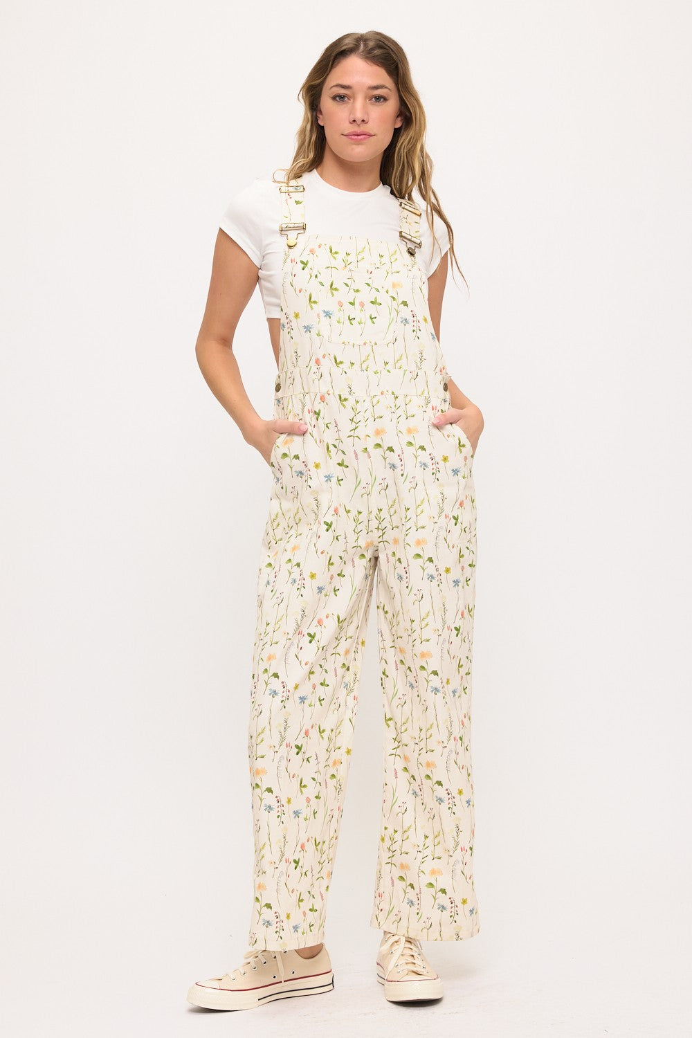 Woman wearing a floral overalls and white t-shirt on a white background