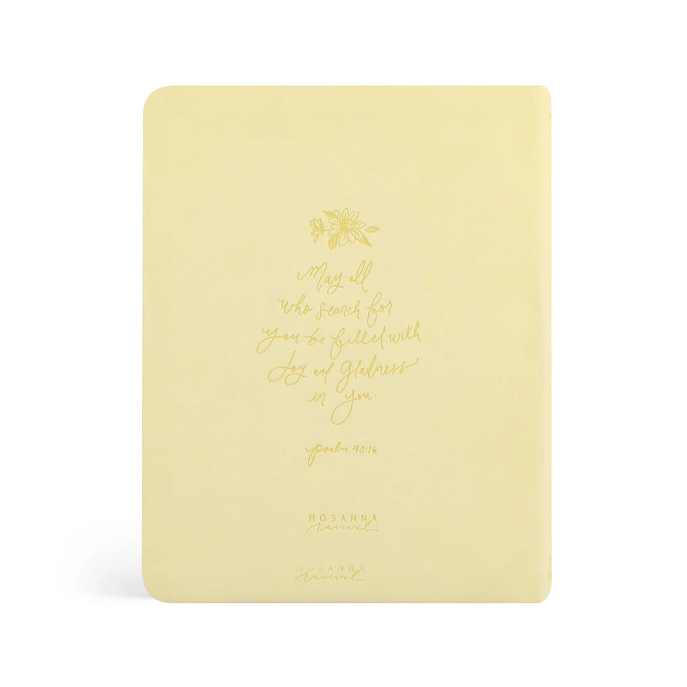Yellow NLT Bible with scripture text and floral design on a white background