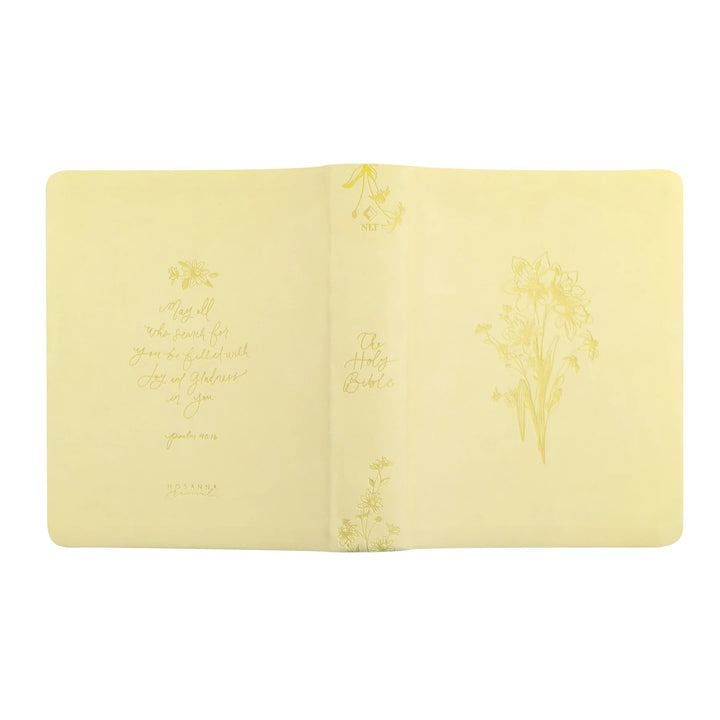 Open yellow Bible with floral designs and scripture on a white background