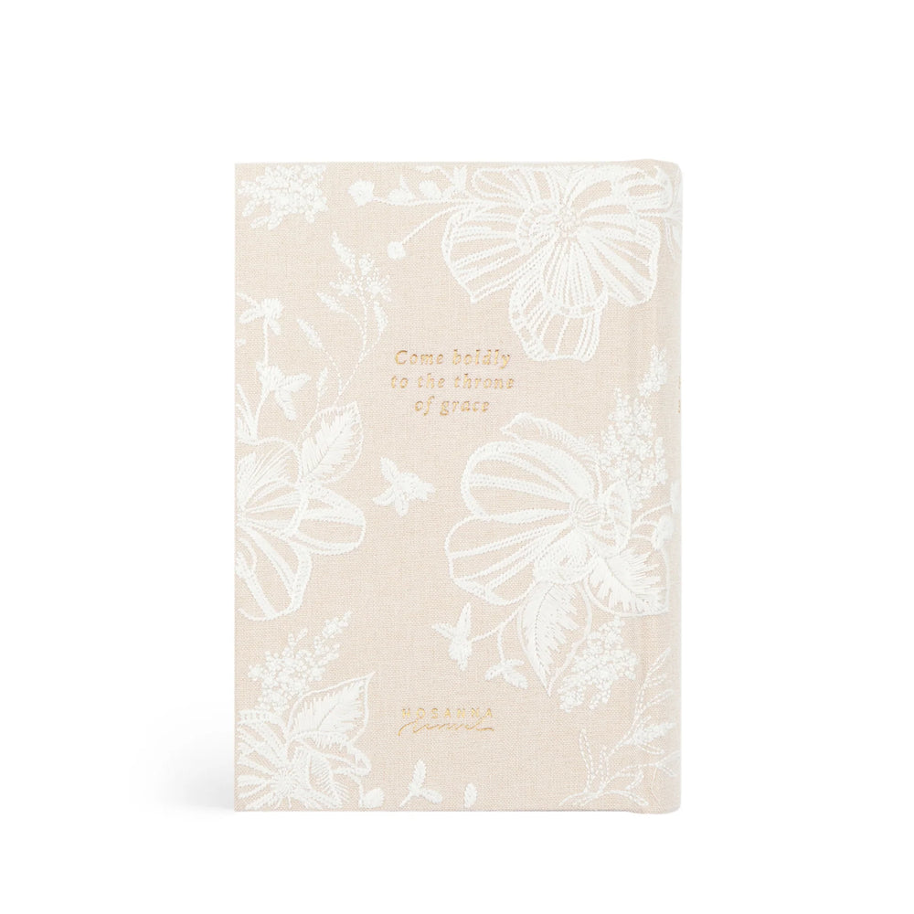 Beige Bible with white embroidered floral patterns and gold text on a white background